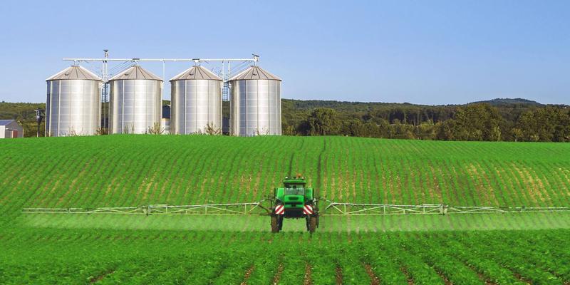 Silos e pulverizador em lavoura